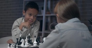 Küçük çocuklar akşamları evde satranç oynuyorlar.