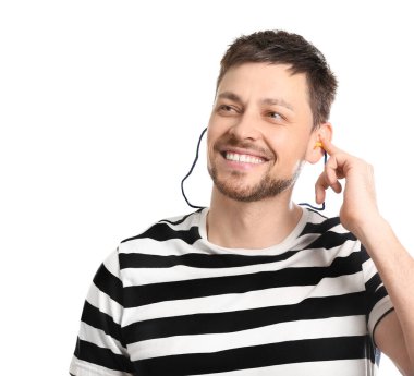 Beyaz arka planda kulak tıkacı olan gülümseyen yakışıklı bir adam.