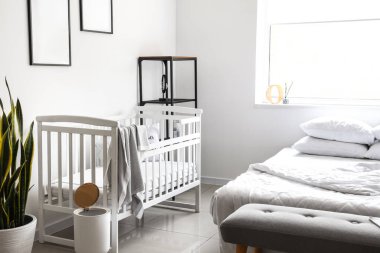 Modern yatak odasındaki beyaz beşik ışık duvarının yanında.