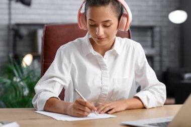 Ofiste çalışırken müzik dinleyen güzel bir genç kadın.