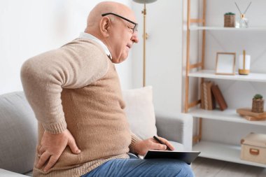 Evdeki kanepede sırt ağrısı çeken defterli son sınıf öğrencisi.