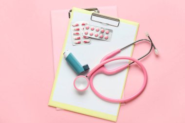 Panolar, steteskop, ilaç paketleri ve renkli fonda astım spreyi.