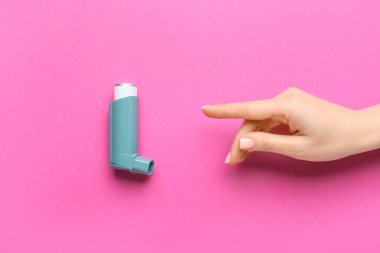 Kadın eli, arka planda astım spreyine işaret ediyor.