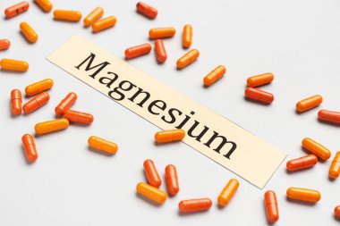 Işık arkaplanı üzerinde renkli kapsüller ve kelime MAGNESIUM