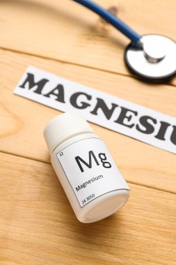 Ahşap arka planda bir şişe magnezyum hapı, yakın plan.