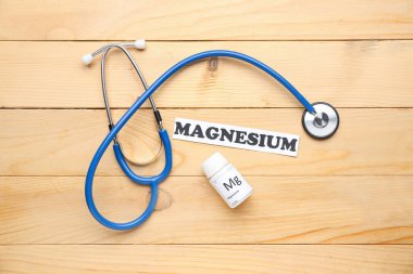 Stetoskop, ilaç şişesi ve tahta arka planda kelime MAGNESIUM