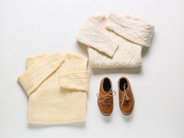 Beyaz arka planda kalın kazaklar ve ayakkabılar