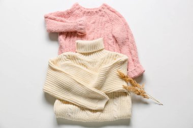 Beyaz arka planda çocuk süveteri ve kamış çiçekleri örüyordu.