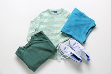 Hafif arka planda şık çocuk kıyafetleri ve ayakkabıları