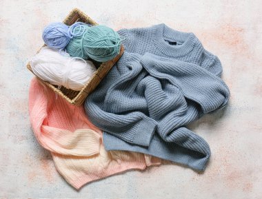 Çocuk süveteri ve sepeti. Arka planda örgü iplikleri var.