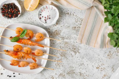 Açık arkaplanda ızgara karides şişi olan tabak.