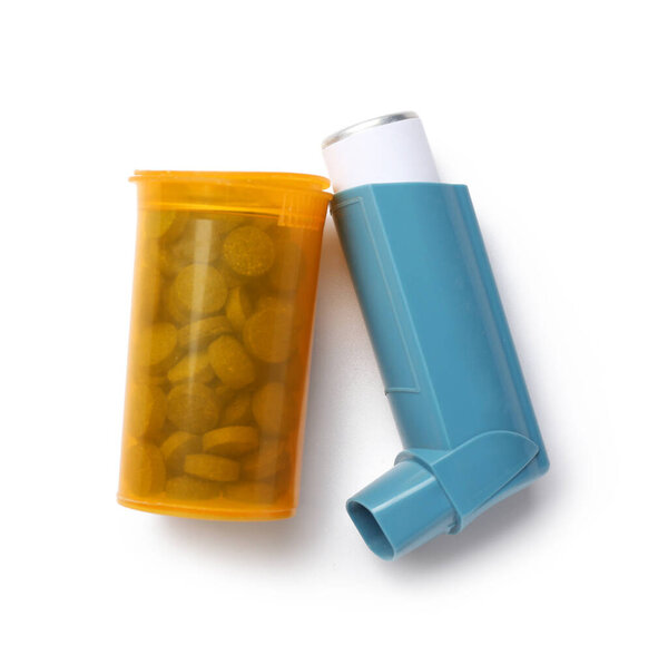 Asthma inhaler and jar of pills on white background