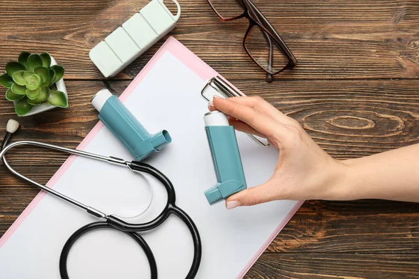 Woman Holding Asthma Inhaler Clipboard Stethoscope Eyeglasses Wooden Background — Stock Photo, Image
