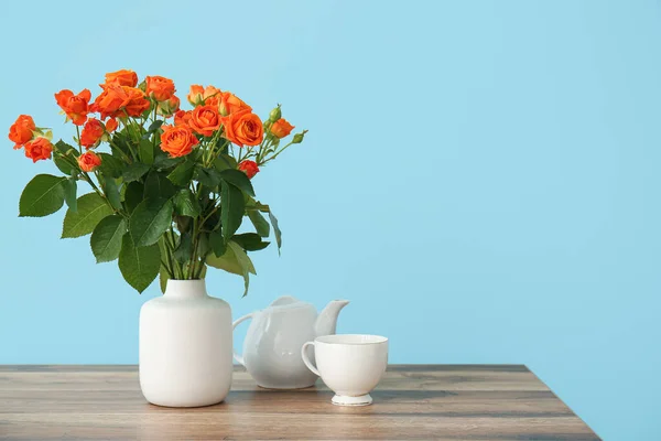 Jarrón Con Hermosas Rosas Naranjas Tetera Taza Mesa Contra Pared — Foto de Stock