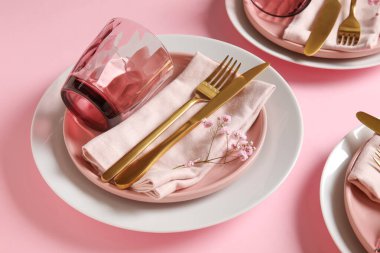 Pembe arka planda çiçekli şenlikli masa ayarları, yakın plan.