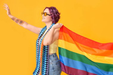 Sarı arka planda LGBT bayrağı olan genç bir kadın.