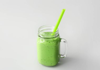 Mason kavanozu açık arkaplanda saman olan yeşil meyve suyu.