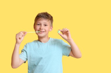 Sarı arka planda sakız çiğneyen mavi tişörtlü küçük çocuk.