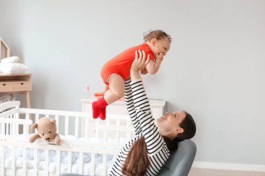 Genç anne küçük bebeğini yatak odasında tutuyor.