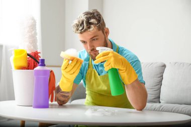 Evde temizlik malzemesi taşıyan yakışıklı bir genç.