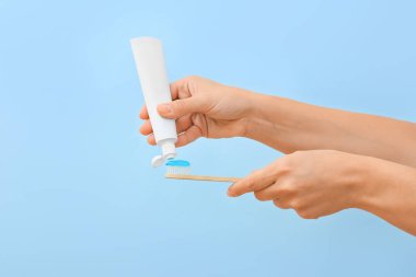 Mavi arka planda diş macunu sıkan kadın.