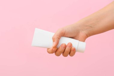 Pembe arka planda diş macunu olan bir kadın eli.