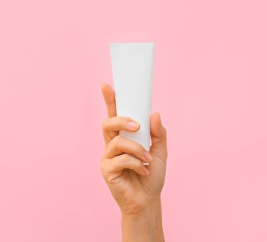 Pembe arka planda diş macunu olan bir kadın eli.