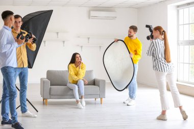 Stüdyoda modelin fotoğrafını çeken genç fotoğrafçılar.