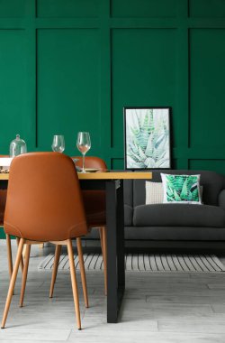 Masası, kanepesi ve yeşil duvarı olan şık bir yemek odası.