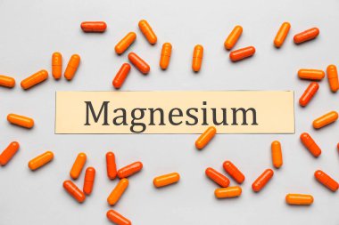 Işık arkaplanı üzerinde renkli kapsüller ve kelime MAGNESIUM