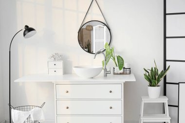 Lavabosu, aynası ve ayakta duran lambası olan hafif banyonun içi.