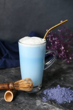 Bir fincan mavi kibrit latte, koyu arkaplanda toz ve chasen.