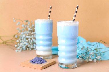 Bir bardak mavi kibrit latte, toz ve renk arkaplan üzerinde çingene çiçeği.