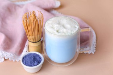 Cam bardak mavi kibrit sütlü latte, arkaplanda toz ve kase.