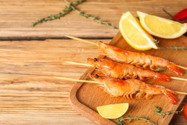 Ahşap arka planda ızgara karides şişleri.