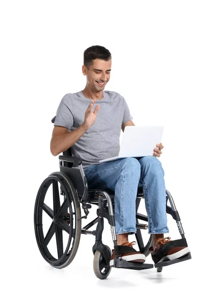 坐在轮椅上的年轻人在白色背景下使用笔记本电脑 — 图库照片