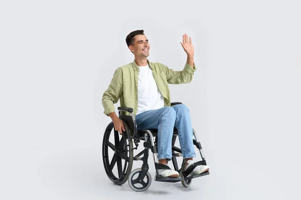 Młody Człowiek Wózku Inwalidzkim Macha Ręką Lekkim Tle — Zdjęcie stockowe