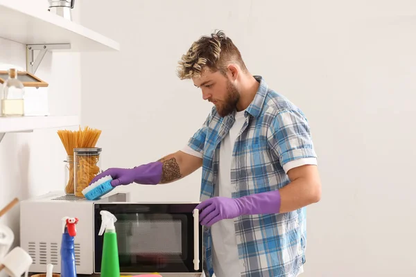 Mutfakta Sünger Temizleme Mikrodalgası Olan Yakışıklı Bir Genç — Stok fotoğraf