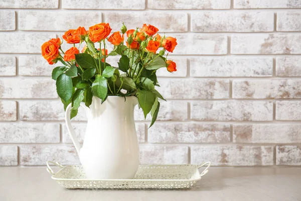 Jug Beautiful Orange Roses Table Brick Wall — Stock Photo, Image