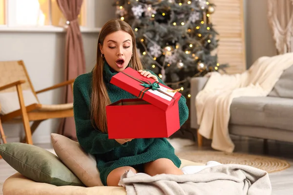 Surprised Young Woman Opening Gift Home Christmas Eve — Stock Photo, Image