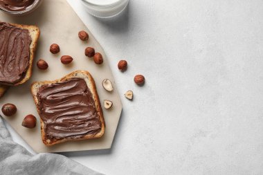 Çikolata ezmeli ekmek tahtası ve fındıklı beyaz arka plan, yakın plan.
