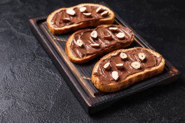 Tahta tahta tahta tahta, çikolata ezmeli ve fındıklı siyah arka plan.