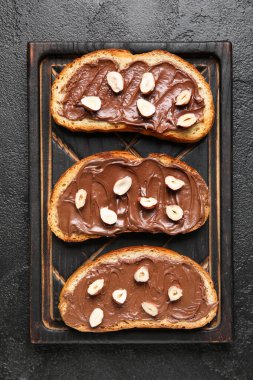 Tahta tahta tahta tahta, çikolata ezmeli ve fındıklı siyah arka plan.