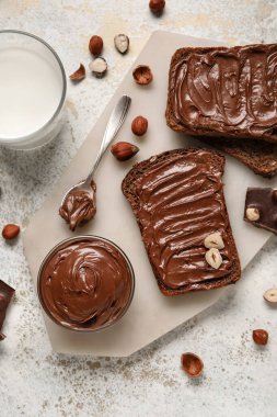 Çikolata ezmeli ekmek, fındık ve arka planda bir bardak süt.