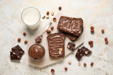 Çikolata ezmeli ekmek, fındık ve arka planda bir bardak süt.