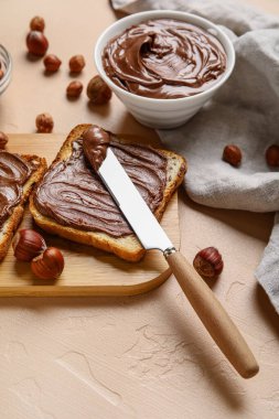 Tahta tahta tahta tahtada çikolata ezmesi ve bej arka planda fındık.