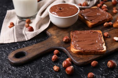 Tahta tahta tahta tahta, çikolata ezmeli ve fındıklı siyah arka plan.