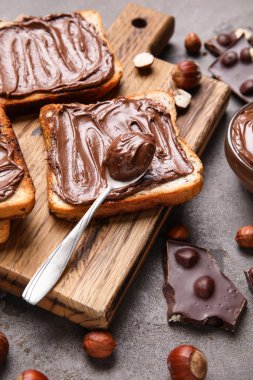 Çikolata ezmeli ahşap tahta tahta ve gri arka planda fındık.