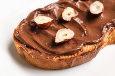 Çikolata ezmeli ekmek ve tabakta fındık, yakın plan.