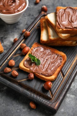 Tahta tahta tahta tahta üzerinde çikolata ezmesi ve fındıklı siyah arka plan, yakın plan
